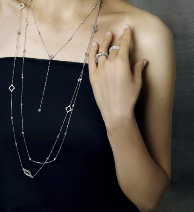 Layered diamond station necklaces worn with stacked diamond rings